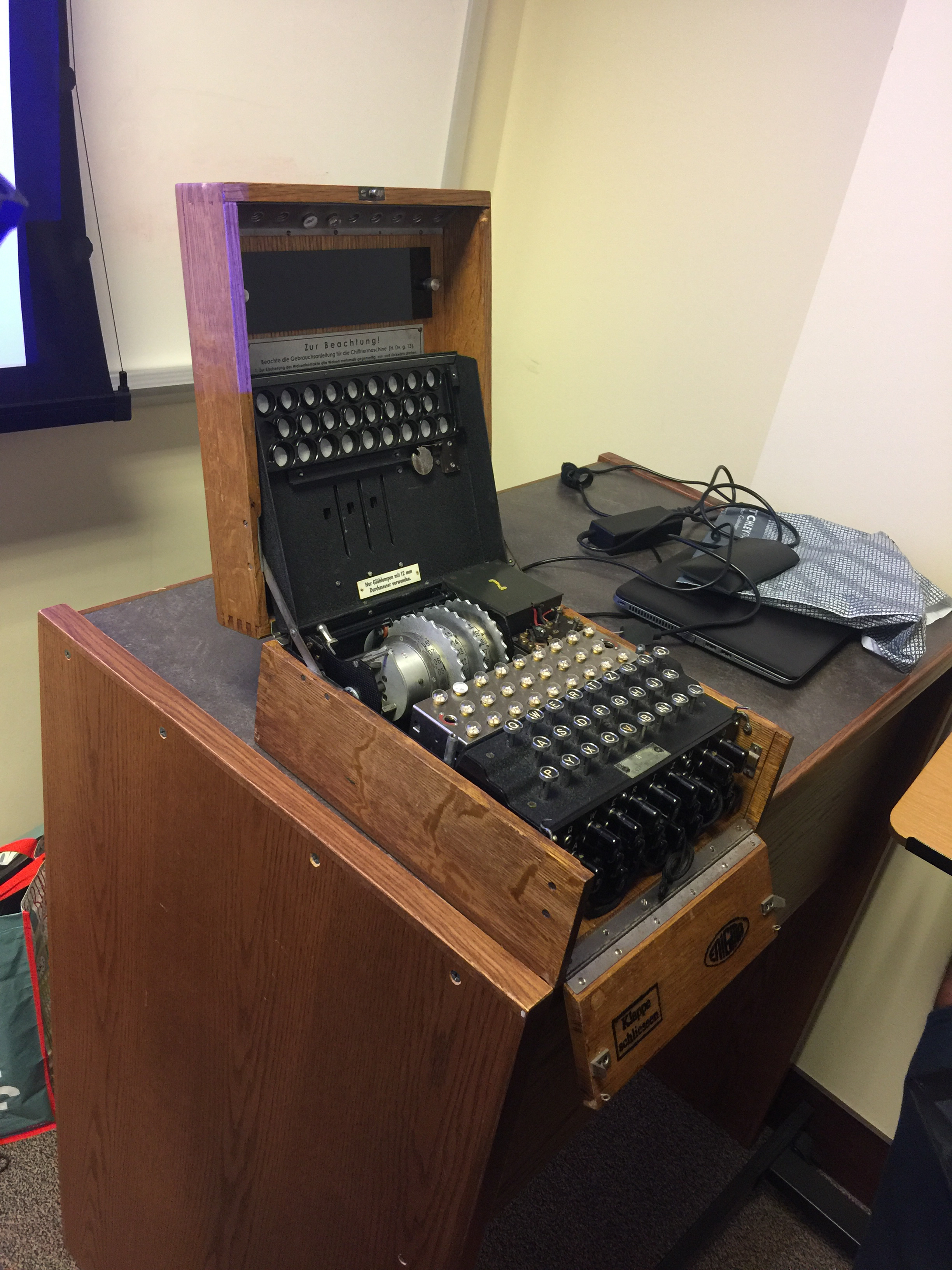 An old wooden enigma machine opened up, with the keyboard and rotors visible